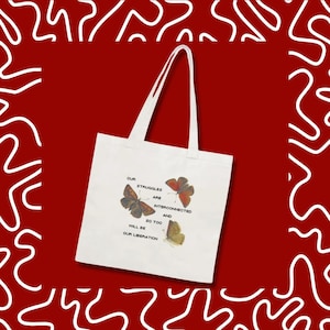 May include: White tote bag with a red background and white abstract design. The bag features three butterfly illustrations and the text: "Our struggles are interconnected and so too will be our liberation."