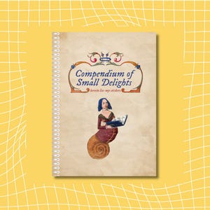 May include: A notebook with a spiral binding, featuring the title "Compendium of Small Delights" and the text "herein lies my stickers." The cover illustration depicts a woman with blue hair and a snail shell body holding a book. The background is a light beige.