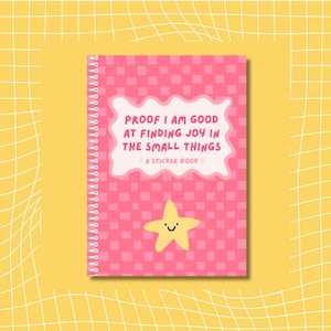 May include: A pink sticker book with a checkered pattern and spiral binding. The cover features the text "PROOF I AM GOOD AT FINDING JOY IN THE SMALL THINGS" in a white cloud-shaped text box, and a yellow star with a smiling face.