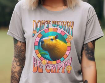 May include: A gray t-shirt with a retro-style graphic of a capybara in a circle with the text "Don't Worry Be Cappy".