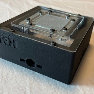 May include: A black box with a clear acrylic lid. The box has a logo on the front that says "K3X". The acrylic lid has a silver mesh filter inside.