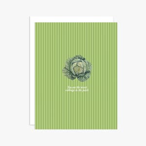 May include: A greeting card with a light green background featuring vertical stripes. In the center, there is a detailed illustration of a green cabbage. Below the cabbage, the text reads: You are the nicest cabbage in the patch.