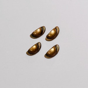 May include: Four small, semi-circular metal drawer pulls with a distressed bronze finish. Each piece features a rounded, domed centre section and a flat, curved base plate, arranged in a two-by-two grid pattern on a plain, neutral surface.