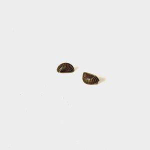 May include: Two small, semi-circular metal drawer pulls with an antique brass finish. Each pull features a series of vertical, raised ridges radiating from the center of the flat base toward the curved top edge, creating a shell-like appearance.