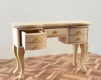 May include: A wooden vanity table with four drawers and gold knobs. The table has a curved top and four legs with a decorative design. The drawers are open, revealing the interior.
