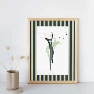 Könnte beinhalten: Abstrakter Kunstdruck in einem Holzrahmen mit gestreiftem Rand. Das Kunstwerk zeigt ein abstraktes Design in Schwarz und Grün auf weißem Hintergrund. Eine beige Vase mit Trockenblumen befindet sich im Vordergrund.