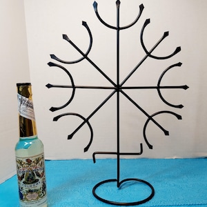 May include: A black metal display stand with a circular base and a snowflake-like design. A bottle of Florida Water cologne is next to the stand. The cologne bottle has a gold foil top and a colorful label.