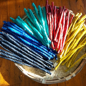 May include: A basket filled with colorful twisted sticks, including blue, teal, yellow, and red.