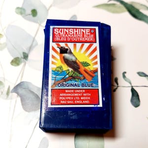 May include: A blue box of Sunshine Ultramarine Blue paint with a bird on the front. The box says "Original Blue" and "Made under arrangement with Polypex Ltd. Middx. HA2 6AU, England."