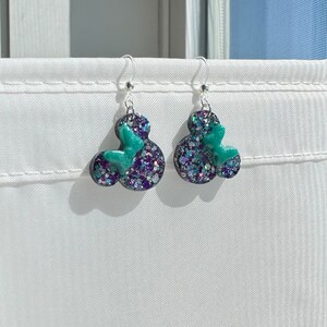 May include: A pair of silver dangle earrings with black and green glitter resin Mickey Mouse heads.