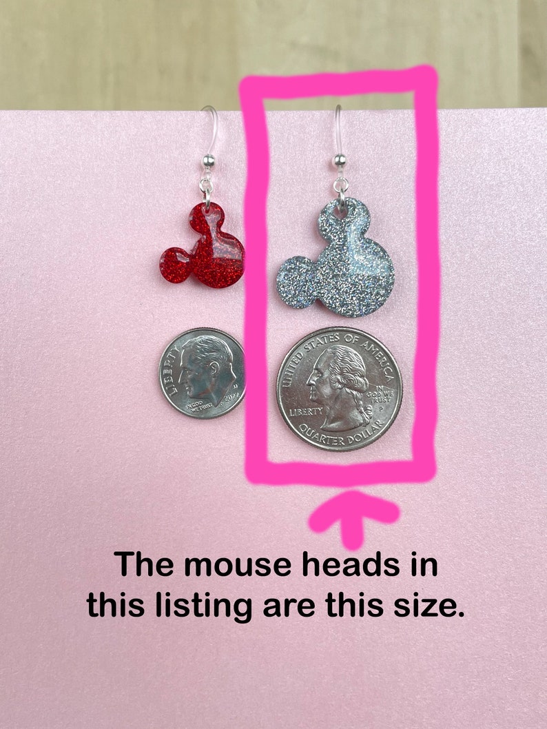May include: A pair of silver dangle earrings with red and silver glitter mouse head charms. The mouse heads are approximately the size of a US quarter.