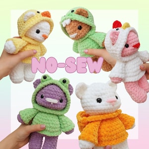 Pu&ograve; includere: Cinque peluche all'uncinetto con maglioni con cappuccio senza cuciture. I giocattoli sono un pulcino giallo, un orso marrone con un costume da dinosauro verde, un maiale rosa con un costume da unicorno bianco, una rana viola con un costume da rana verde e un orso bianco con un maglione arancione.