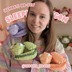 May include: A woman holding three crocheted dragon plushies in shades of green, orange, and purple. The dragons are curled up, with white accents on their wings and bellies. Text on the image reads "(Almost) No-Sew Sleepy Dragon" and "@nooks_hooks".