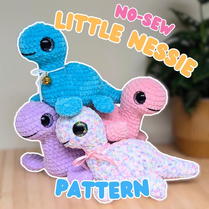 May include: A stack of four crocheted Nessie-like plush toys in blue, pink, purple, and a multi-colored pastel. The blue Nessie has a small gold bell on its neck. The text "NO-SEW LITTLE NESSIE PATTERN" is displayed in the image.