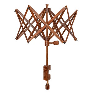 May include: A wooden yarn swift with a clamp base. The swift is made of dark brown wood and has a starburst design. The clamp is made of the same wood and has a screw to tighten it.