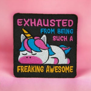 May include: Black embroidered patch with a white unicorn with a pink mane and blue horn, sleeping with the text "Exhausted from being such a freaking awesome" in yellow, pink, and blue.