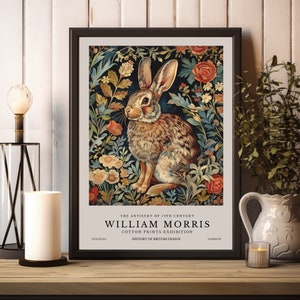 May include: A vintage-style poster featuring a brown rabbit sitting in a field of colorful flowers. The poster is titled "The Artistry of 19th Century William Morris Cotton Prints Exhibition" and includes the text "Textiles, History of British Design, London".