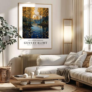 May include: A framed art print featuring a landscape painting with a river and trees in shades of gold, blue, and green. The print is labeled "20TH CENTURY EXHIBITION GUSTAV KLIMT". The artwork hangs above a light-colored sofa in a living room setting.
