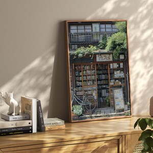 May include: A framed photograph of a bookstore in Japan. The storefront is covered in greenery and has a sign that reads "花屋". A bicycle is parked in front of the store.