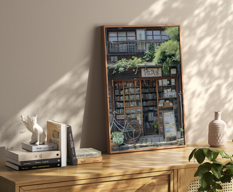 May include: A framed photograph of a bookstore in Japan. The storefront is covered in greenery and has a sign that reads "花屋". A bicycle is parked in front of the store.