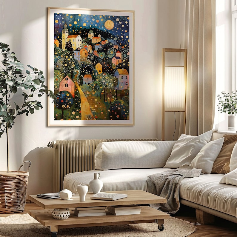 May include: A framed painting of a whimsical village scene with colorful houses, trees, and a winding path. The sky is filled with stars and a crescent moon. The painting is set against a white wall in a living room setting.