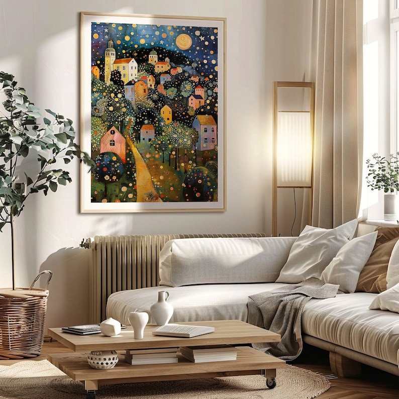 May include: A framed art print depicting a whimsical village scene under a starry night sky. The artwork features colorful houses, a winding path, and a large moon, creating a dreamlike atmosphere. The print is displayed in a living room setting.