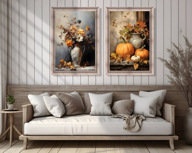 May include: Two framed paintings with a fall theme. The first painting features a white vase with orange and yellow flowers. The second painting features a white pitcher with three pumpkins.