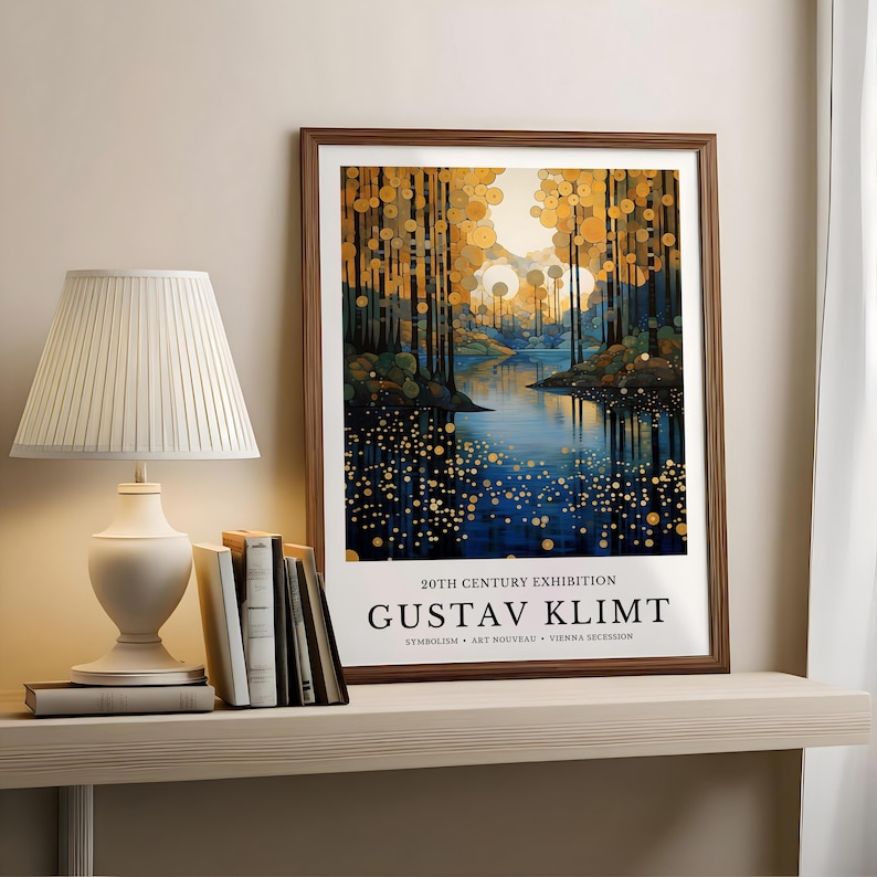 May include: A framed art print featuring a landscape painting with a river and trees in shades of blue, gold, and brown. The print is labeled "20TH CENTURY EXHIBITION" and "GUSTAV KLIMT". A white lamp and books sit on a shelf.