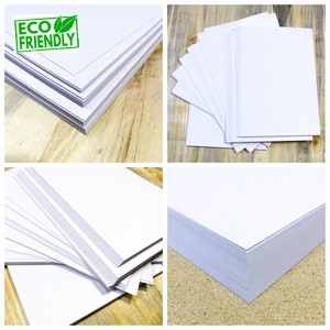 May include: A stack of white paper, with a green "ECO FRIENDLY" label on the top sheet. The paper is on a wooden surface.