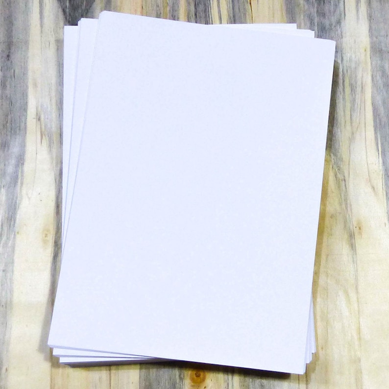 May include: A stack of white paper sheets on a wooden surface.