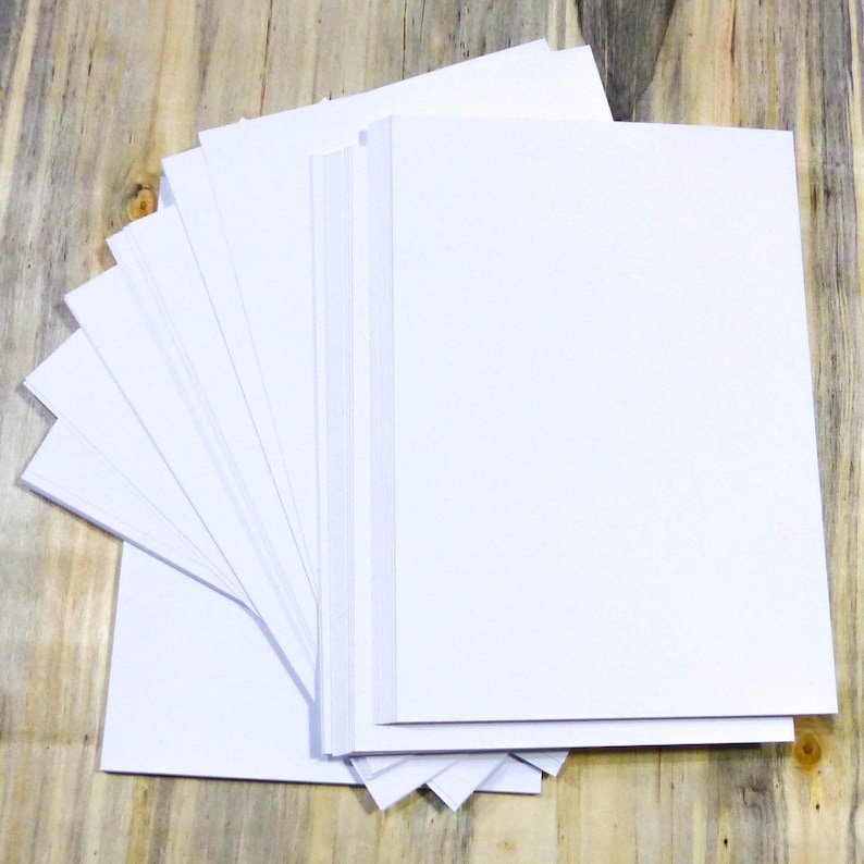 May include: A stack of white paper sheets fanned out on a wooden surface.