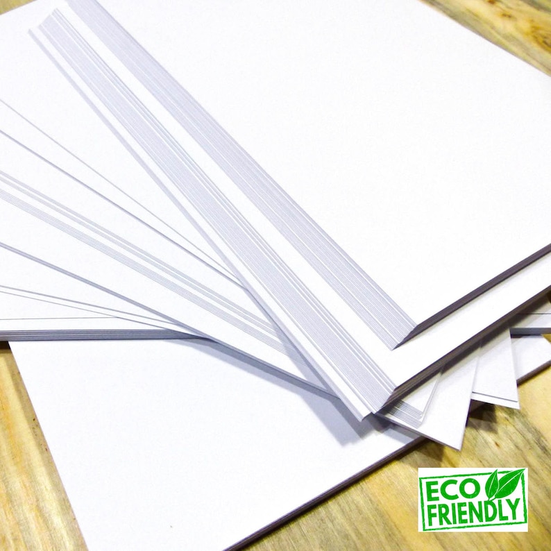 May include: A stack of white paper sheets, with the top sheet folded over to reveal the edges of the other sheets. The paper is eco-friendly.