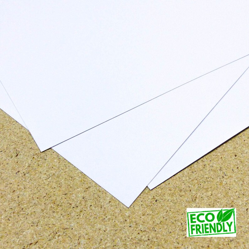 May include: Stack of white cardstock paper, eco-friendly, on a brown surface.