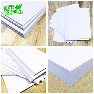 May include: A stack of white paper, with a green "ECO FRIENDLY" label on the top sheet. The paper is on a wooden surface.