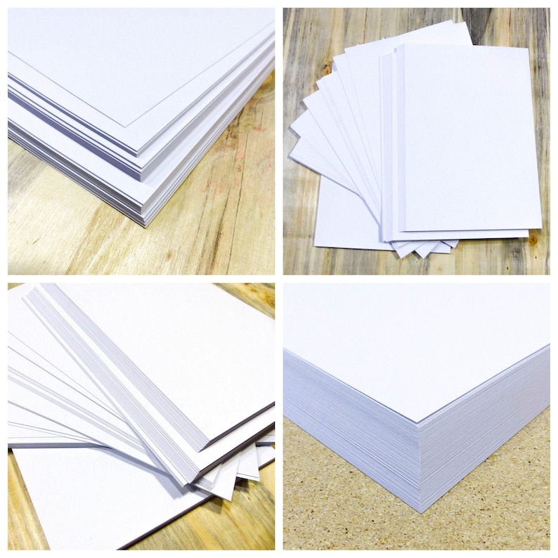 May include: Four stacks of white cardstock paper on a wooden surface. The stacks are arranged in different configurations, showing the paper's smooth texture and crisp edges.