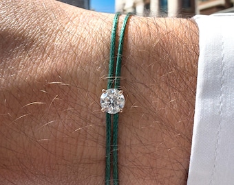 May include: A green string bracelet with a single round diamond set in a gold setting.
