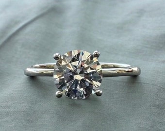 May include: A silver ring with a large, clear, round-cut diamond.