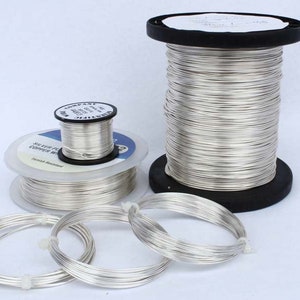 May include: Two spools of silver-plated copper wire, one large and one small, with several coils of wire laid out on a white surface. The spools are labeled "Silver Plated Copper Wire".
