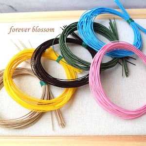 May include: Assortment of colourful craft wire in various colours, including yellow, pink, brown, blue, and green. The wire is wound into coils and is ready for crafting projects.