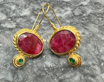 May include: Gold earrings with a pink oval gemstone and a smaller green gemstone. The earrings have a twisted wire design.