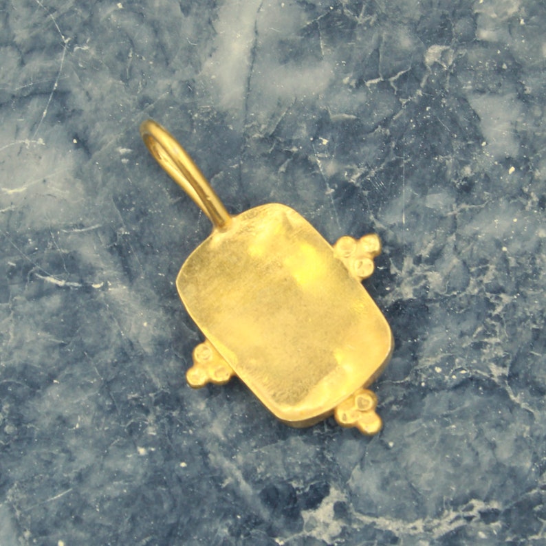 May include: Gold pendant with a rectangular shape and a smooth, polished finish. The pendant has four small, decorative accents on the edges.