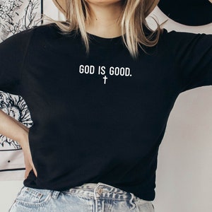 May include: Black t-shirt with white text that reads "GOD IS GOOD." and a small white cross below the text.