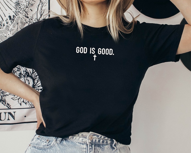 May include: Black t-shirt with white text that reads "GOD IS GOOD." and a small white cross below the text.
