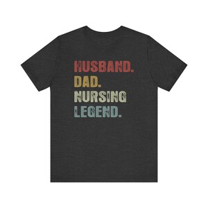 May include: Dark heather grey t-shirt with a vintage-style graphic that reads "Husband. Dad. Nursing Legend."
