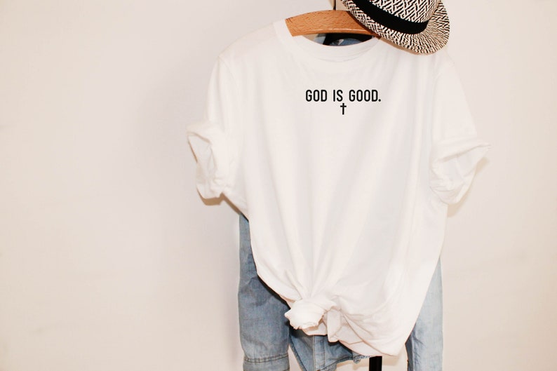 May include: White t-shirt with the text "GOD IS GOOD." and a small cross symbol below the text.