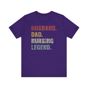 May include: Purple t-shirt with the text "Husband. Dad. Nursing Legend." in a vintage style font with a rainbow color gradient.