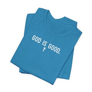 May include: A folded blue t-shirt with the text "GOD IS GOOD." and a white cross symbol.