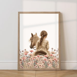 May include: A young girl in a brown dress rides a light brown horse through a field of pink and white flowers.
