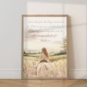 May include: A framed print featuring a watercolor illustration of a girl riding a white horse through a field of wildflowers. The artwork includes the text "Trust in the Lord with all your heart, and do not lean on your own understanding. Proverbs 3:5-6."