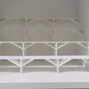 Op de afbeelding: Witte kunststoffafscheiders voor een kast of kledingkast. De scheiders creëren meerdere compartimenten om spullen op te bergen.